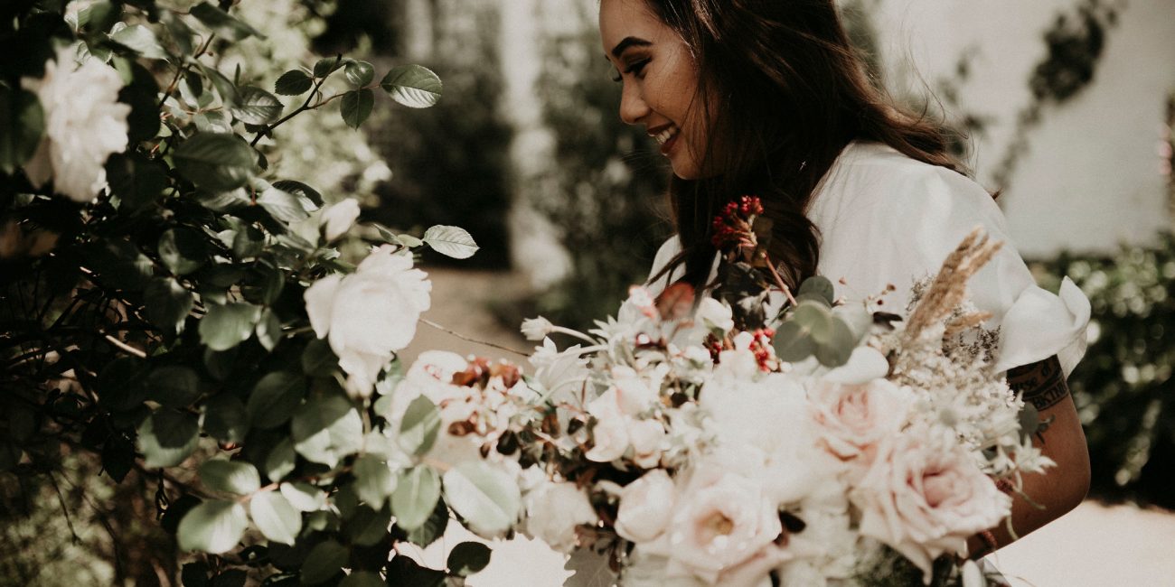 Bride stops to smell the roses in the garden holding her bouquet Elopement and Wedding Photography Melbourne Photographer Sarah Matler