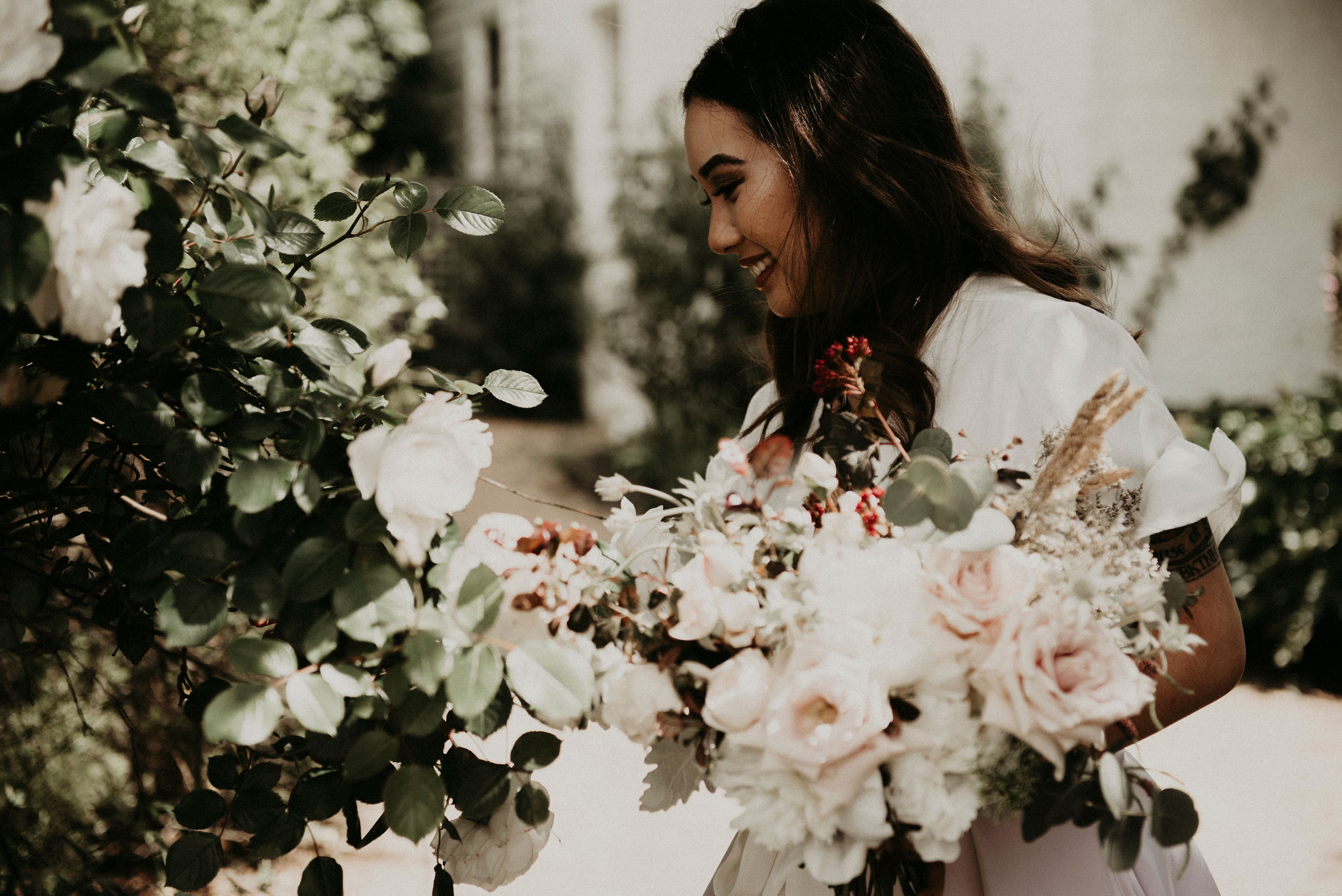 Bride stops to smell the roses in the garden holding her bouquet Elopement and Wedding Photography Melbourne Photographer Sarah Matler